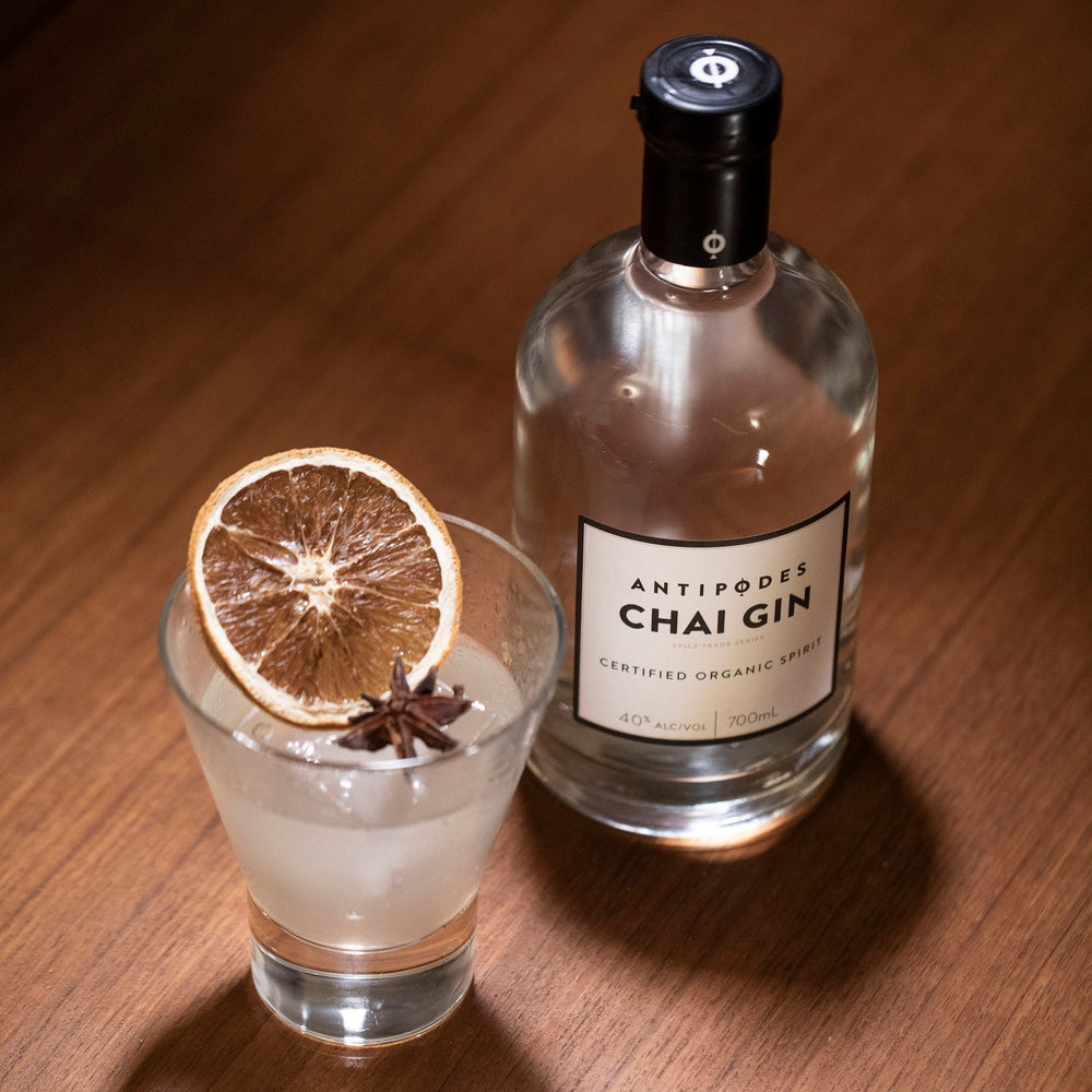 Bottle of Chai Gin with a glass of gin and tonic on a wooden surface
