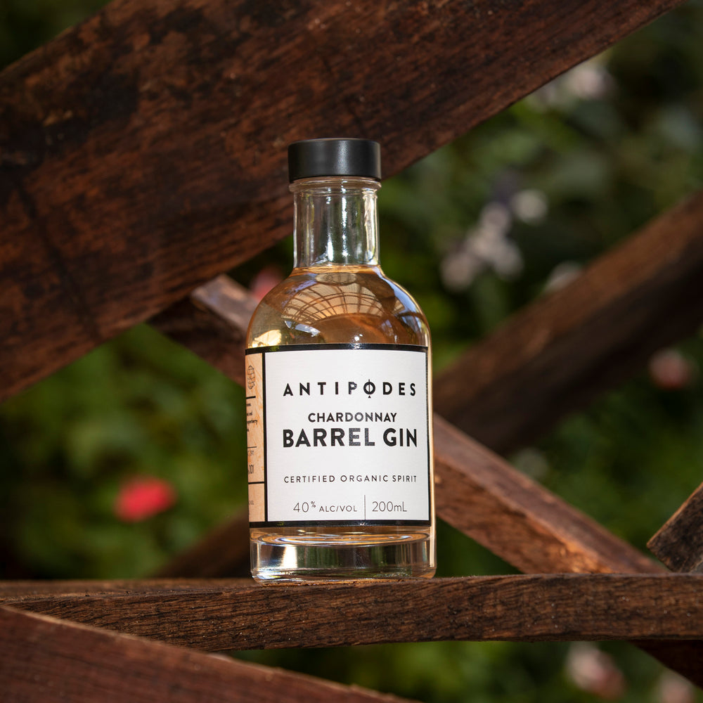 Bottle of Antipodes Chardonnay Barrel Gin on a wooden surface with a blurred natural background