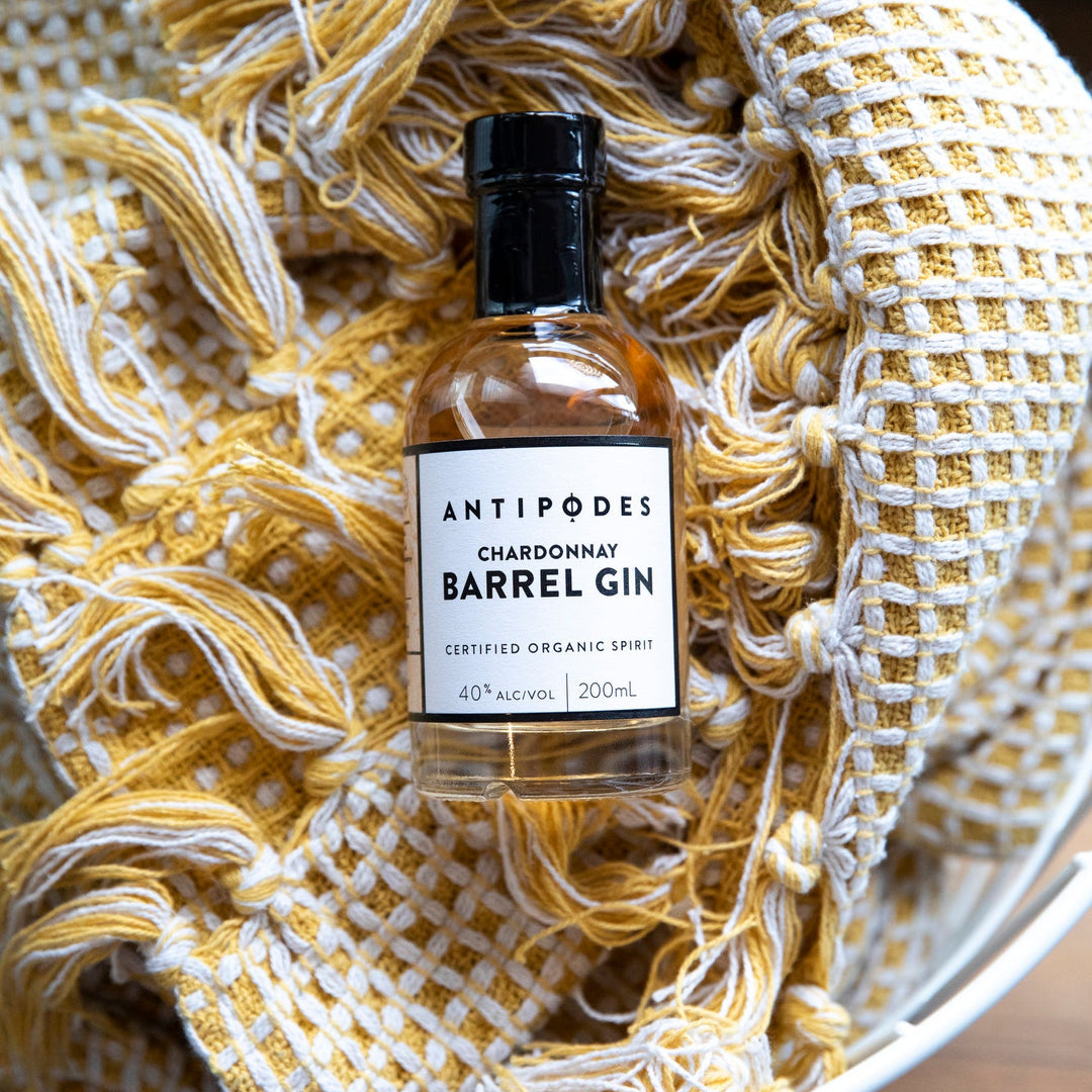Bottle of Antipodes Chardonnay Barrel Gin on a textured yellow and white fabric background