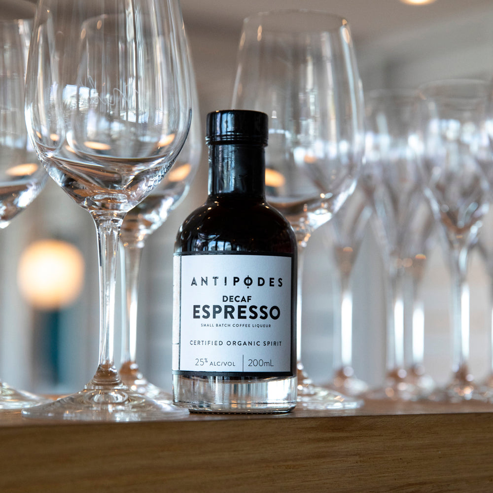 Bottle of Antipodes Decaf Espresso liqueur with wine glasses in the background