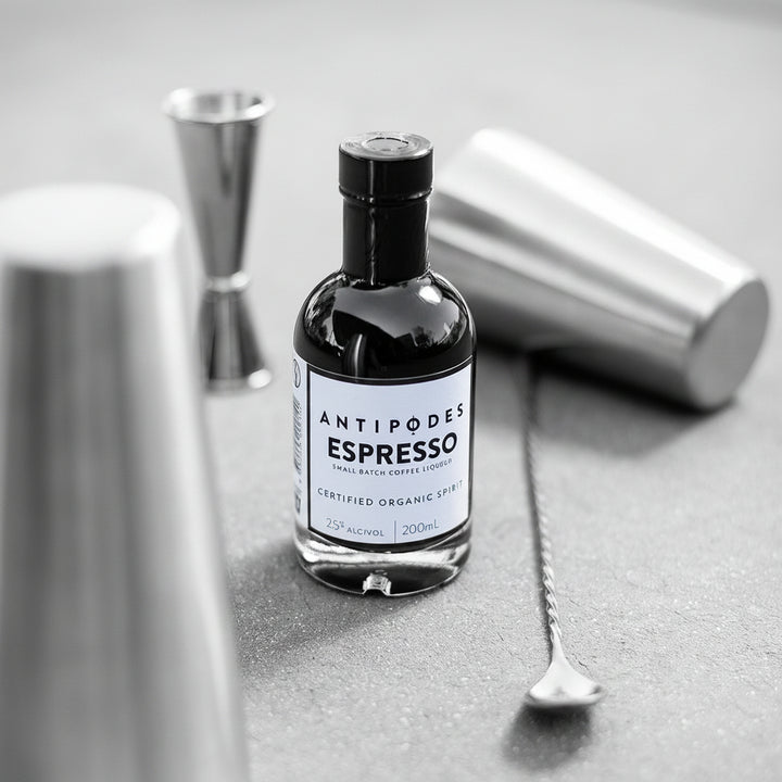 Bottle of Antipodes Espresso on a gray surface with bar tools in the background