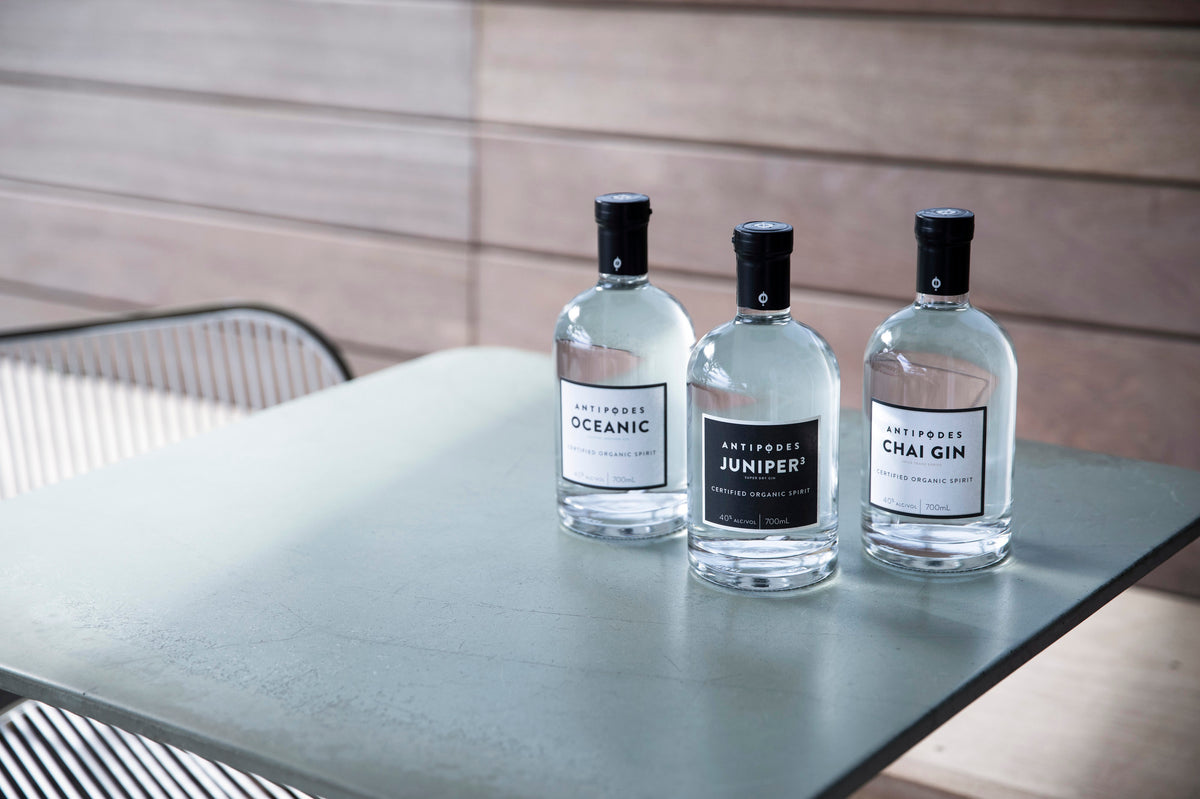 Three bottles of gin on a table with a neutral background