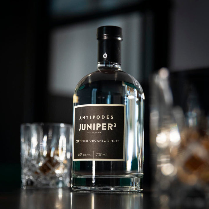Bottle of Antipodes Juniper3 gin on a bar with glasses in the background