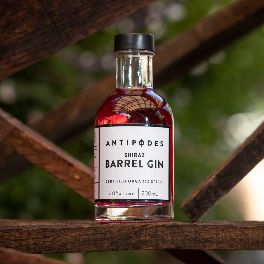 Bottle of Antipodes Shiraz Barrel Gin on a wooden surface with a blurred natural background
