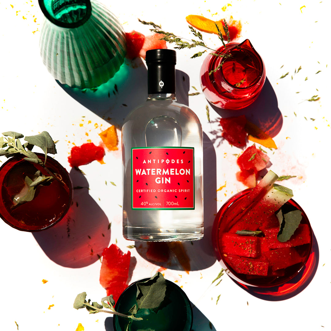 Bottle of Antipodes Watermelon Gin surrounded by garnished cocktails on a white background